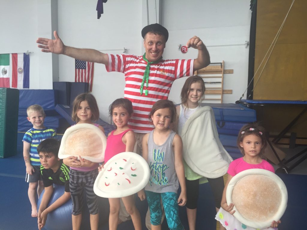 Costumed coach with kids holding pizza props at a circus birthday party