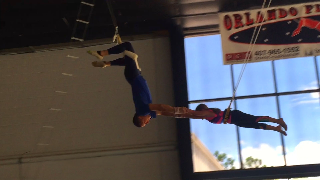A flyer reaching for the catcher mid-air on the flying trapeze